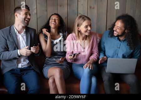 Gruppo eterogeneo di amici che si divertono a trascorrere del tempo con i gadget Foto Stock