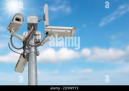 Gruppo di telecamere di sicurezza (CCTV) o telecamera di sorveglianza su palo isolato su sfondo blu del cielo. Foto Stock