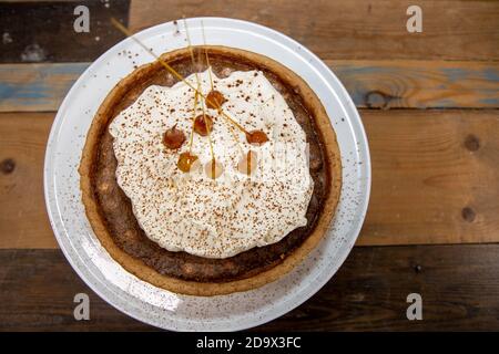 Una deliziosa torta del deserto di una Toffee Bonfire e nocciola crostata su un piano di lavoro di cucina in legno Foto Stock