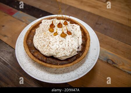 Una deliziosa torta del deserto di una Toffee Bonfire e nocciola crostata su un piano di lavoro di cucina in legno Foto Stock