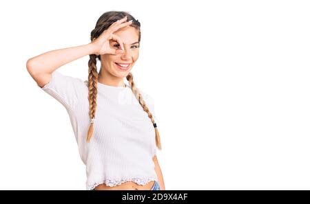 Bella donna caucasica con capelli biondi che indossa trecce e bianco tshirt sorridente felice di fare ok segno con mano su occhio guardando attraverso le dita Foto Stock