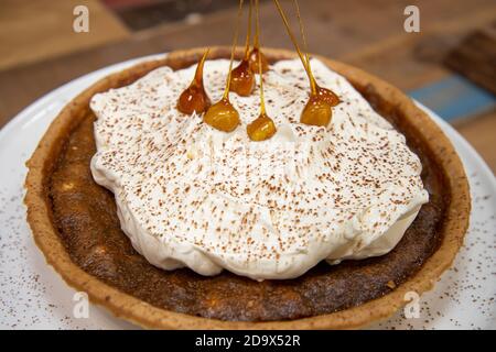 Una deliziosa torta del deserto di una Toffee Bonfire e nocciola crostata su un piano di lavoro di cucina in legno Foto Stock
