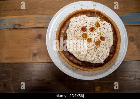 Una deliziosa torta del deserto di una Toffee Bonfire e nocciola crostata su un piano di lavoro di cucina in legno Foto Stock