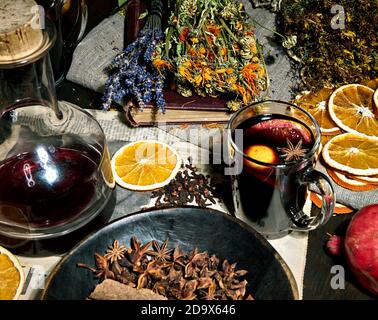 Sfondo sfocato con VIN brulé, chiodi di garofano, anice stellato, cannella, arance secche, libro antico, bottiglia d'annata, lavanda, calendula Foto Stock