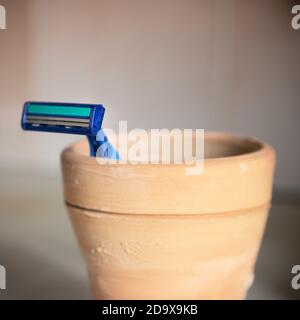 Un rasoio blu si trova in tazza di argilla nel bagno. Foto Stock