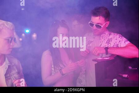 I giovani sniffing la droga in nightclub con le luci laser colorate Foto Stock