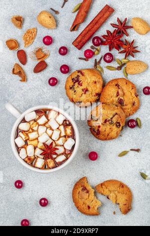Cioccolata calda (caffè, cacao) con marshmallows in una tazza bianca e biscotti fatti in casa con mirtilli rossi, mandorle e spezie (cannella, anice stellato, cardam Foto Stock