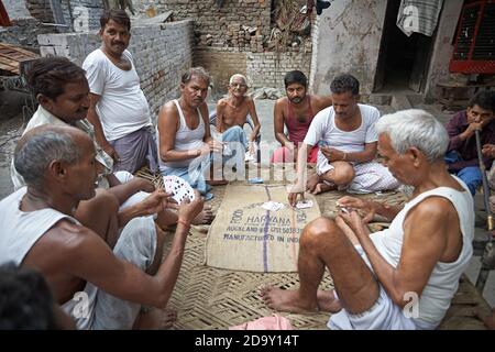 Delhi, India, luglio 2009. Uomini che giocano carte fuori di una casa in una baraccopoli. Foto Stock