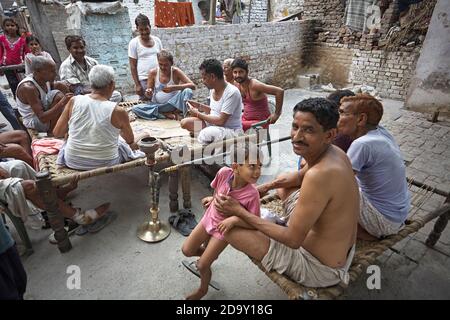 Delhi, India, luglio 2009. Uomini che giocano carte fuori di una casa in una baraccopoli. Foto Stock