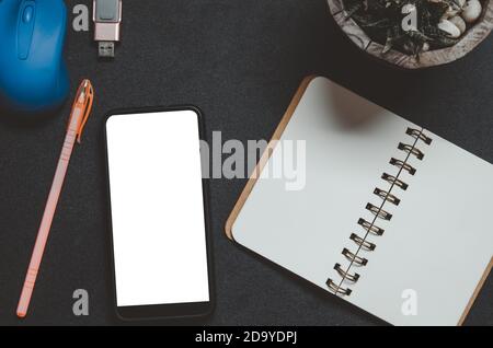 Guarda lo smart phone con mouse, penna e notebook su sfondo nero. Foto Stock