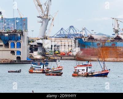 Tradizionali barche da pesca in legno ancorate di fronte ad un grande cantiere navale a Laem Chabang, il più importante porto commerciale della Thailandia. Foto Stock