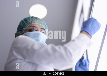 Medico in occhiali e maschera medica e guanti è tenuta un'immagine a raggi X. Foto Stock