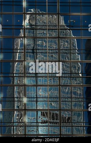 I piani superiori di uno degli edifici più alti del mondo, l'International Finance Center Two (IFC2), alto 420 m (1,378 piedi), sono contornati e distorti in una massa di metallo e vetro aggrovigliati quando si vedono riflessi nel rivestimento sul lato del J.P. Morgan Office Tower a Chung WAN o Central District a Hong Kong, Cina. Foto Stock