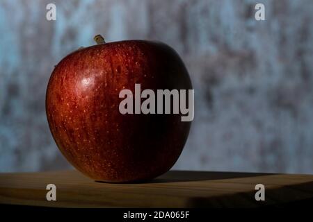 Una sola Apple rossa Braeburn su una textured fuori fuoco sfondo Foto Stock