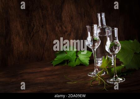 Vodka d'uva, pisco - bevanda alcolica forte peruviana tradizionale in bicchieri eleganti su tavolo di legno d'annata, spazio copia Foto Stock