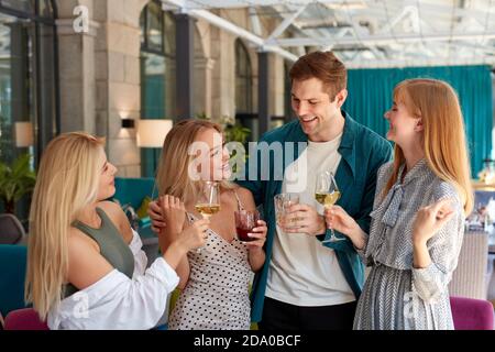 gruppo di giovani caucasici che festeggiano il compleanno con un bicchiere di bevanda, donne e uomo si sono riuniti in ristorante per congratularsi con l'uomo di compleanno Foto Stock