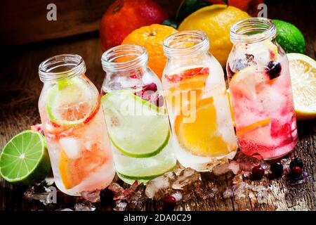 Limonata fredda agli agrumi: Limone al ribes nero, arancio, lime e mirtillo, pompelmo e arancio sanguinante con ghiaccio tritato in una piccola bottiglia, selec Foto Stock