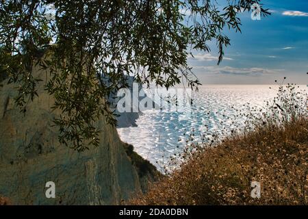 Scogliera bianca in Kerkyra Corfù Grecia e celeste mare blu in una baia con sabbia marrone e spiaggia argillosa Foto Stock
