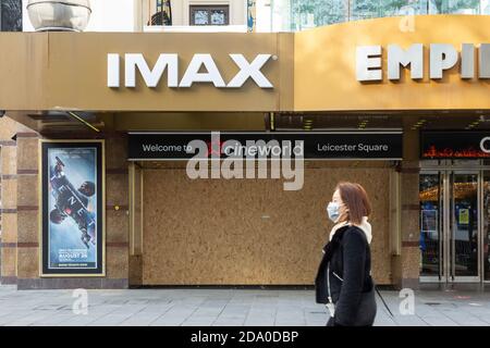 Pedone in maschera di faccia passeggiate oltre il teatro IMAX in Leicester Square, chiuso durante il secondo blocco nazionale, Londra, 7 novembre 2020 Foto Stock