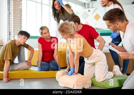 Gruppo di giovani diversi pratica di addestramento di primo soccorso a mano, corso di primo soccorso in CPR manichino. Concetto di abilità di formazione per salvare vite umane, medicina Foto Stock