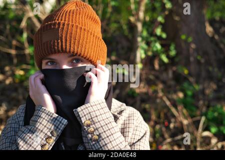 la ragazza adolescente copre la bocca e il naso con una sciarpa Come protezione contro il virus di Convid-19 all'età di pandemia Foto Stock