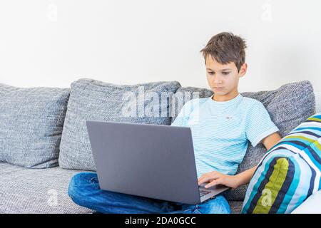 Bambino che usa il computer portatile a casa. Tecnologia, apprendimento online, formazione a distanza, studio a casa, compiti, giochi educativi per bambini Foto Stock