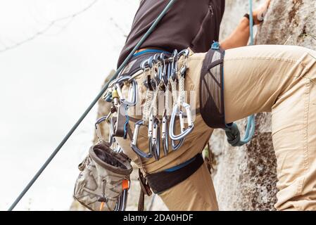 Crop alpinista maschile sportivo arrampicata su scogliera a strapiombo in estate giorno Foto Stock