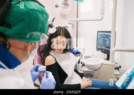 Dall'alto del raccolto ortodontista irriconoscibile che dimostra mascella gettata a. donna etnica attenta in clinica Foto Stock