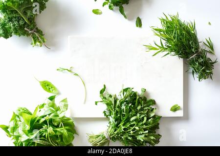 Piatto con varie erbe e lattuga e taglio di marmo lavagna su sfondo bianco Foto Stock