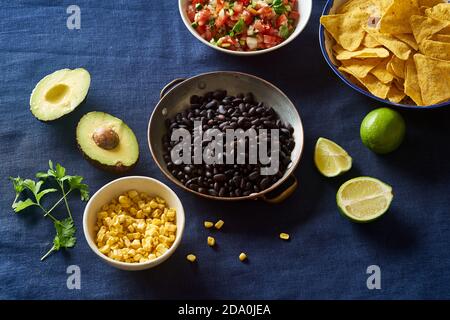 Ingredienti per cucinare i peperoncini - fagioli neri, patatine di tortilla, mais e salsa Foto Stock