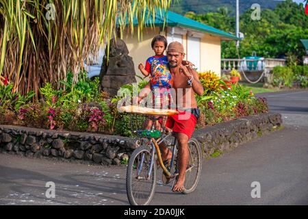 Uomo Tahitiano con sua figlia che porta baguette mentre si cavalcano una bicicletta sull'isola di Tahiti, Polinesia francese, Tahiti Nui, Società Isole, Frenc Foto Stock