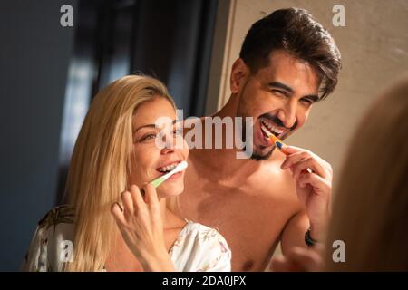 Bell'uomo bearded abbracciando allegra ragazza mentre sfregava i denti insieme in bagno al mattino Foto Stock