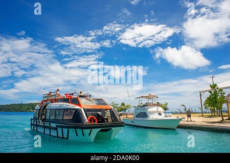 Teens saltando in acqua accanto a Bora Bora Vaitape dock, Isole della Società, Polinesia francese, South Pacific. Foto Stock