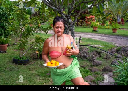 Donna che taglia la frutta del mango con il coltello affilato a Moorea, Polinesia francese, Isole della Società, Sud Pacifico. Cook's Bay. Foto Stock