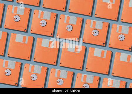 Layout vista dall'alto con set di floppy per computer arancione vintage dischi disposti in righe su sfondo grigio Foto Stock