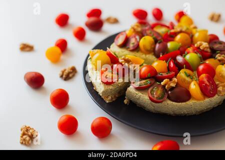 Dall'alto di quiche casalinghe appetitose con pomodori colorati guarniti con erbe e noci servite su tavola bianca Foto Stock