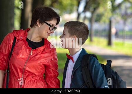 Mamma e figlio adolescente vanno dopo la scuola. L'amore della madre, l'educazione dei figli, la fiducia nei rapporti familiari. Foto Stock