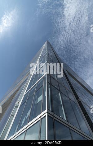 Dal basso di futuristico grattacielo costruito con finestre di vetro situato in centro città, a ridosso del cielo blu Foto Stock