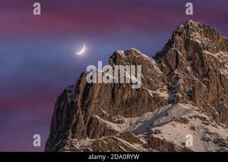 Basso angolo di incandescente ceretta crescente in cielo luminoso sopra Bridly Pirenei coperti di neve di notte Foto Stock