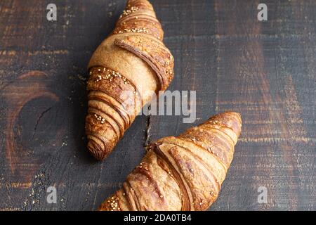 Croissant dolci disposti su tavolo di legno con tazza di aromatico caffè per la colazione a casa Foto Stock