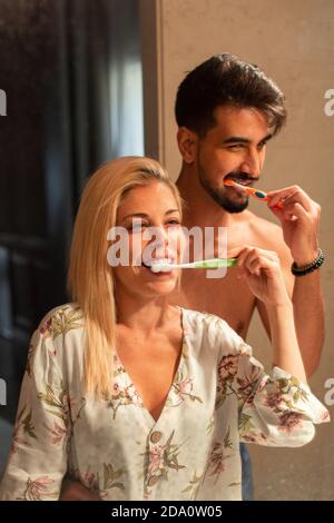 Bell'uomo bearded abbracciando allegra ragazza mentre sfregava i denti insieme in bagno al mattino Foto Stock