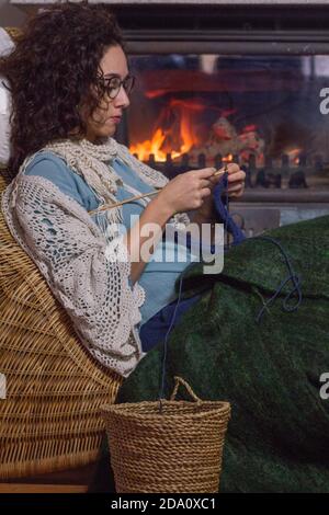 Primo piano di donna che si maglietta in una stanza accogliente con camino che brucia sullo sfondo. Anche teapots come decorazione. Foto Stock