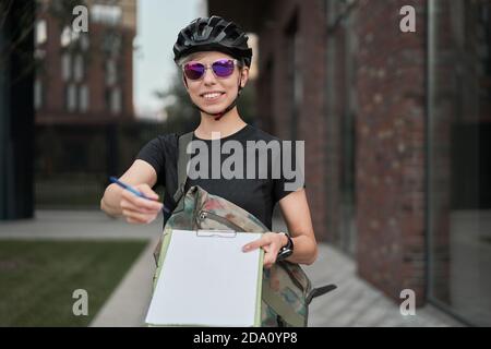 Felice Donna ciclista corriere con penna in mani su strada il giorno d'estate Foto Stock