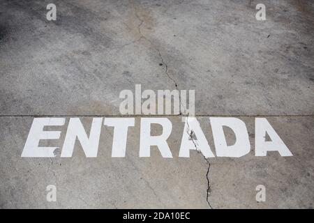 Dall'alto di strada asfaltata scabciata con iscrizione Entrada disegnato con vernice bianca Foto Stock