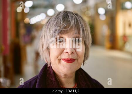 Ritratto di bella donna di mezza età con capelli corti che cammina all'interno del centro commerciale. Foto Stock