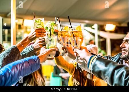 Gruppo di amici felici che bevono e tostano un cocktail al bar - concetto di amicizia con i giovani che si divertono insieme mentre beva mojito e spri Foto Stock
