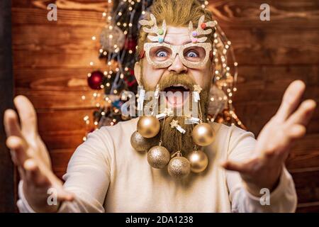 Santa divertente. Preparazione di Natale - uomo che festeggia il nuovo anno. Santa felice vestita in abiti invernali pensa a Natale vicino albero di Natale. Tema Foto Stock