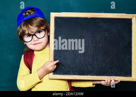 Gli studenti sorridenti che disegnano alla scrivania. Bambino sorridente allegro alla lavagna. In aula. 1 settembre. Ritorno a scuola. Foto Stock