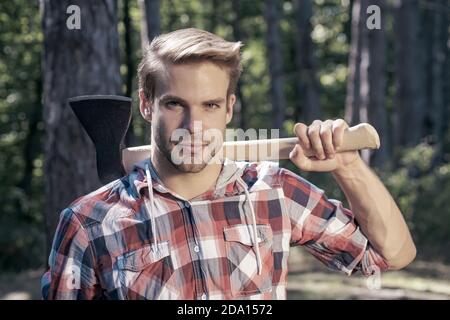 Lumberjack porta l'ascia sulla spalla. Deforestazione. Bell'uomo con ascia. Lumberjack nel bosco con un'ascia. Foto Stock