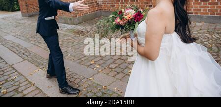 Lo sposo sta dando una mano alla sposa. Coppia nuziale insieme festeggiando felice giorno di nozze. Foto Stock